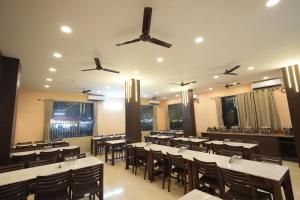 a restaurant with tables and chairs and ceiling fans at Hotel SagarPriya in Digha