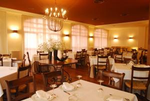 a restaurant with white tables and chairs and a chandelier at Hotel Iguareña in Ezcaray