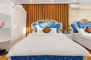 a bedroom with a large white bed with blue headboards at Van Don Royal Hotel in Hà Cái