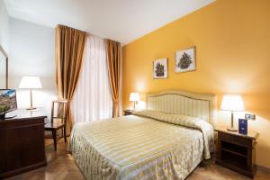 una camera d'albergo con un letto, una scrivania e due lampade di Hotel Isabella a Taormina