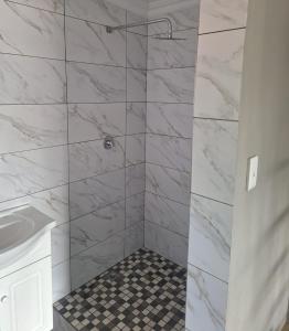 a bathroom with a shower with white marble walls at 42AtSouth in Vryheid
