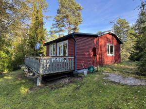 a red cabin with a porch in a field at The Hunters Hill - Cosy private forest retreat in Brålanda