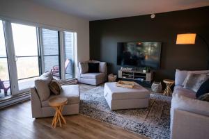 een woonkamer met banken en een flatscreen-tv bij 211 - Bright Condo - Pool and Cozy Atmosphere in Baie-Saint-Paul +62 foto's
