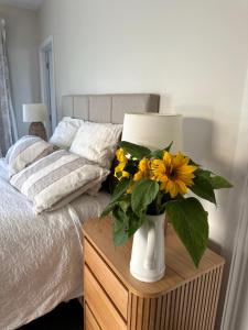 a vase with yellow flowers on a table next to a bed at The Garden Room in Clyde
