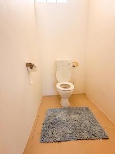 a bathroom with a toilet with a blue rug at Lakaz Riviere Banane in Trèfles