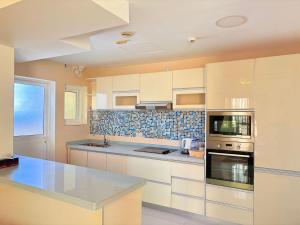 a kitchen with white cabinets and a blue tile wall at A'Sinamar Hotel Apartment in Muscat