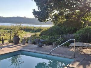 a swimming pool with a chair and a table at Sunrise Cottage in Wilderness