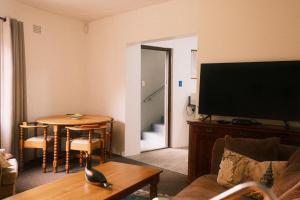 a living room with a couch and a table with a television at Sunrise Cottage in Wilderness