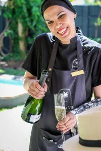 a woman holding a wine bottle and a glass at Palm La Vie in Worcester