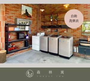 a kitchen with three washing machines and a brick wall at 森林寓 Forest Inn in Minxiong