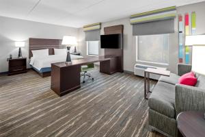 een hotelkamer met een bed, een bureau en een bank bij Hampton Inn and Suites Camp Springs in Camp Springs