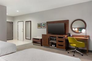 a bedroom with a tv and a desk with a yellow chair at Hampton Inn Lake Charles in Lake Charles