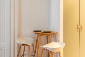 a small table with two white stools in a room at Cosy studio - 2P - Bellecour in Lyon +5 photos