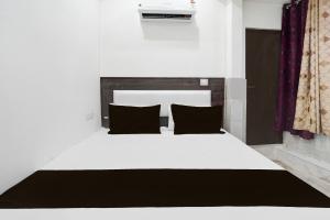 a bedroom with a white bed with black pillows at Hotel O AB Rooms in Bareilly