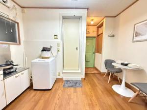 a kitchen with a refrigerator and a table with chairs at Nogata RelaxingHome E2 in Tokyo