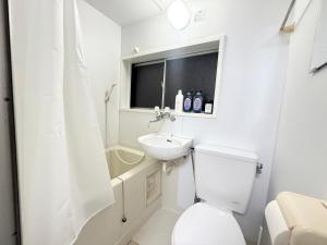a white bathroom with a toilet and a sink at Nogata RelaxingHome E2 in Tokyo