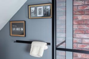 a towel rack with two pictures and a brick wall at Les chambres du Bocage - Chambre Marylin in Bressuire