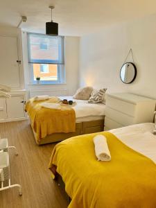 a bedroom with two beds with yellow sheets and a window at Charming 6 Bed Flat in Bedminster - Sleeps 8 in Bristol