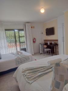 a bedroom with two beds and a table and a television at Nkosazana Guest House in Durban
