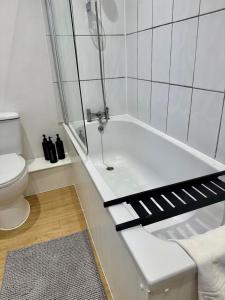 a white bathroom with a tub and a toilet at Charming 6 Bed Flat in Bedminster - Sleeps 8 in Bristol