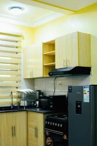 a kitchen with a black refrigerator and wooden cabinets at Eternal shine serenity in Munyonyo +5 photos
