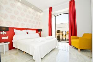 ein Schlafzimmer mit einem weißen Bett und einem gelben Stuhl in der Unterkunft The Zentral Arenal Suites in Sevilla