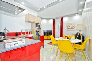 eine Küche mit roten und weißen Arbeitsflächen und gelben Stühlen in der Unterkunft The Zentral Arenal Suites in Sevilla