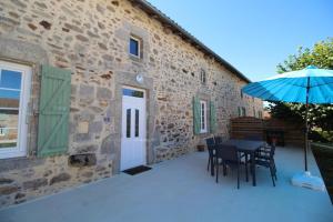 een terras met een tafel, stoelen en een parasol bij Gîte Les Champs N°1 in Saint-Mathieu