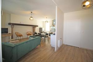 een woonkamer met een groene bank en een keuken bij Gîte Les Champs N°1 in Saint-Mathieu