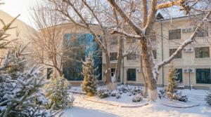a building with snow covered trees in front of it at Wellmore Resort in Yusufkhona