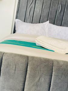 een bed met een grijs matras en kussens erop bij Zayana Homes in Meru