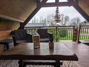 a wooden table on a porch with a view of a fence at Le Moment Normand in Émalleville