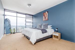 una camera blu con un letto e una grande finestra di Skyline Hideout XL King Bed FREE Parking Views a Edenvale