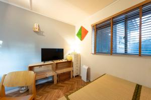 a living room with a television and a desk at Bushido Kashiwa in Kashiwa