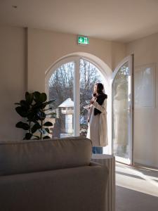 a woman standing in a living room looking out the window at Berghotel Lindenhof in Siegsdorf