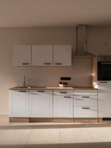 a kitchen with white cabinets and a sink at Berghotel Lindenhof in Siegsdorf
