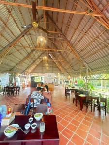 een groep mensen die aan tafels in een restaurant zitten bij Nam Cat Tien Riverside Retreat in Tân Phú