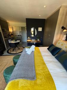 a hotel room with a large bed with a yellow blanket at The Den Apartements Stellenbosch in Stellenbosch