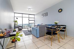 un soggiorno con un divano blu e un tavolo di Skyline Hideout XL King Bed FREE Parking Views a Edenvale