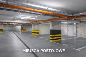 an empty parking garage with orange pipes on the ceiling at InPoint Smart Apartments in Krakow