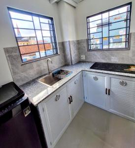 a kitchen with white cabinets and a sink and two windows at PHUONG LAN Homestay in Quy Nhon