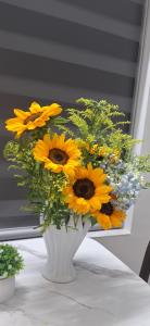 a white vase filled with yellow flowers on a table at PHUONG LAN Homestay in Quy Nhon