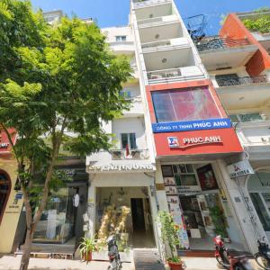 a tall white building with shops on a street at Cát Tường Hotel in Ho Chi Minh City +8 photos