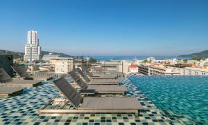 a swimming pool with lounge chairs on top of a building at Gu Hotel Patong in Patong Beach