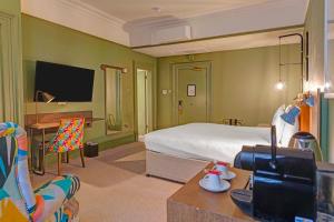 a bedroom with a bed and a desk with a tv at Bristol Grand by Sunday in Bristol