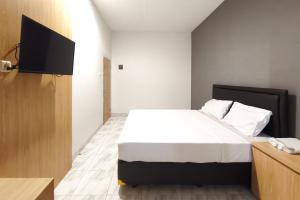 a bedroom with a bed and a flat screen tv at INNCA Singa Utara, Semarang in Alastuwo