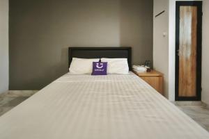 a large white bed with a purple bag on it at INNCA Singa Utara, Semarang in Alastuwo