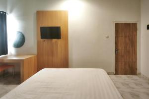 a bedroom with a bed and a tv and a door at INNCA Singa Utara, Semarang in Alastuwo +5 photos