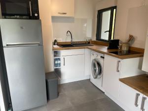 a kitchen with white cabinets and a washer and dryer at Appartement - Hossegor Lac in Hossegor +2 photos