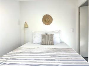 a white bedroom with a bed with a striped blanket at Appartement - Hossegor Lac in Hossegor